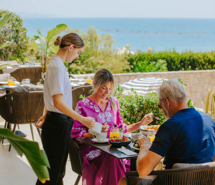 Couple eating breakfast while getting served coffee at Royal Apollonia Aura restaurant