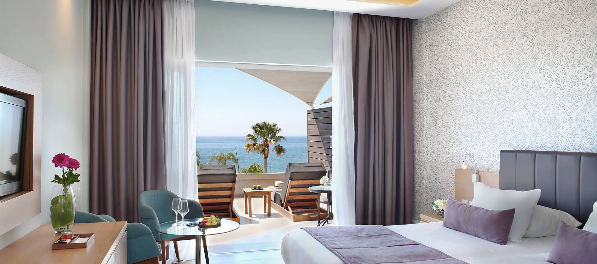 Royal Apollonia Deluxe room bedroom and balcony with sea view and sunbeds