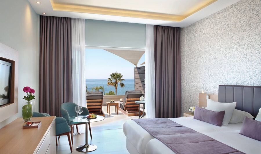 Royal Apollonia Deluxe room bedroom and balcony with sea view and sunbeds