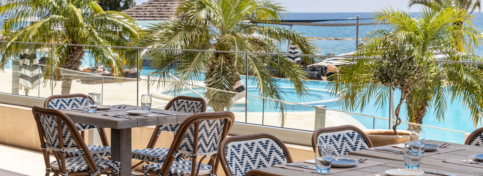 Outdoor tables with pool view at Royal Apollonia restaurant