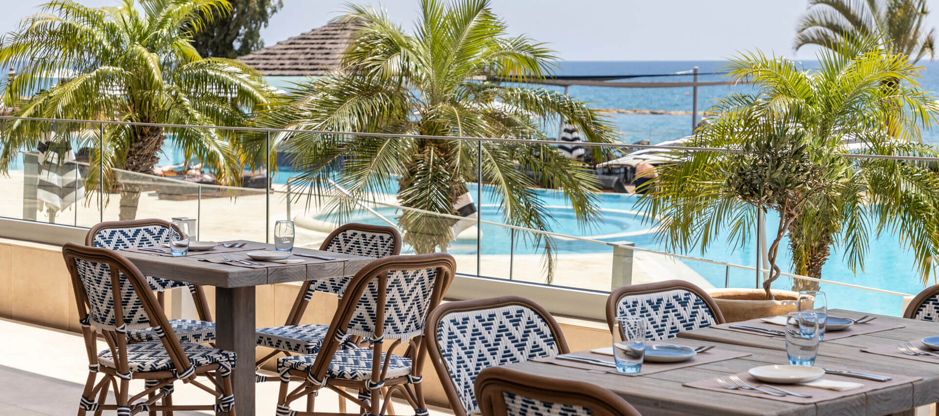 Outdoor tables with pool view at Royal Apollonia restaurant