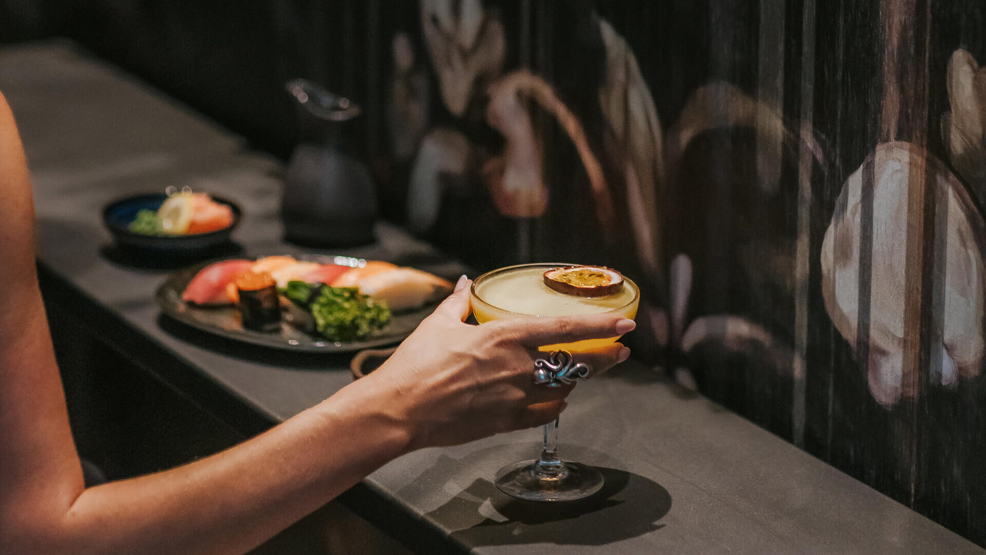 Woman getting a cocktail with asian dishes
