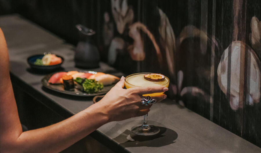 Woman getting a cocktail with asian dishes