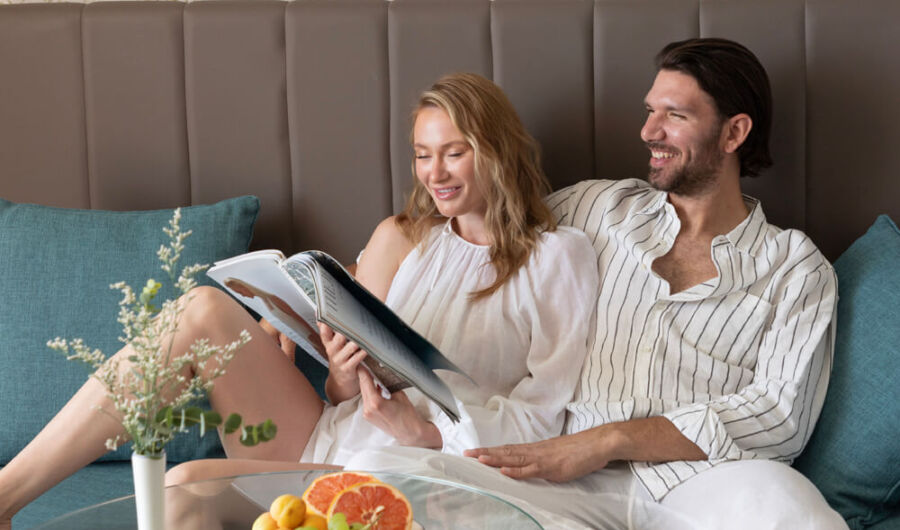 Couple in bathrobes reading magazine on couch