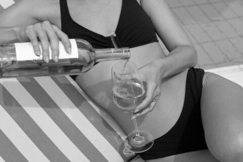 Woman drinking wine lying on sunbed
