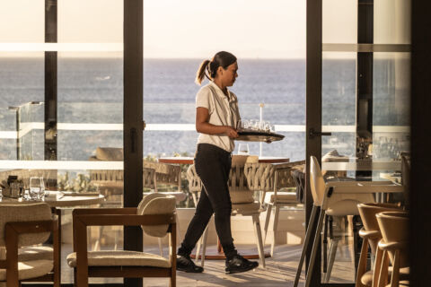 Waiter serving glasses at tables at Valmar Corfu