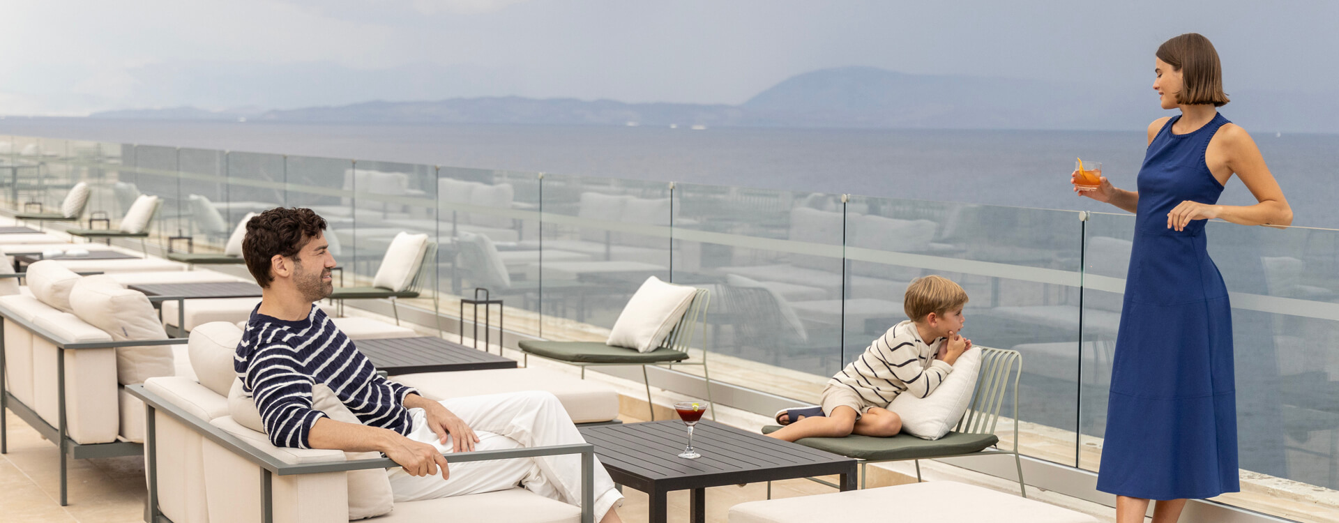 Family relaxing on couches at rooftop restaurant at Valmar Corfu Tarazza