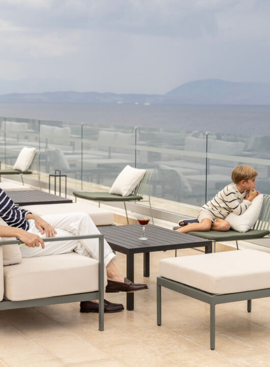 Family relaxing on couches at rooftop restaurant at Valmar Corfu Tarazza